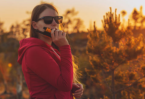 Woman talking into a walkie talkie in the outdoors.