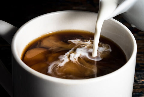 Creamer being poured into a cup of coffee.