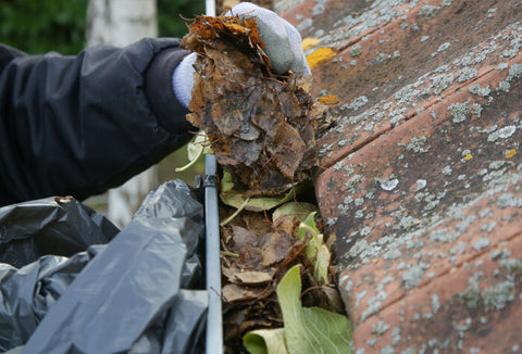 Person cleaning out the gutters on their roof.