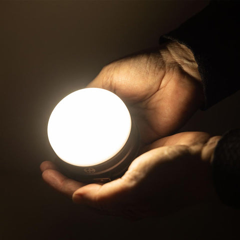 Hand holding a lit USB Lantern and Power Bank in the dark
