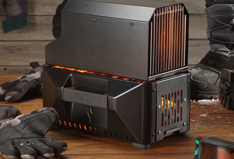 The VESTA unit, a compact heater and stove powered by canned heat, sitting on top of a wood table.