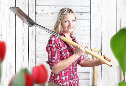 Woman holding a shovel over her shoulder.