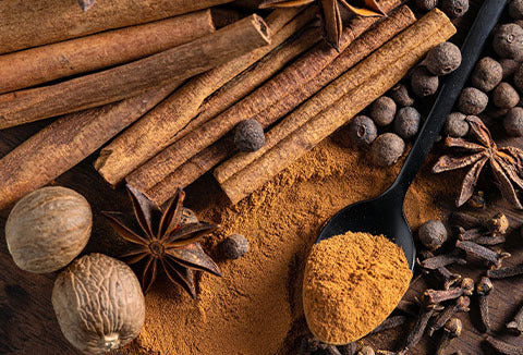 A group of cinnamon sticks together on a brown background.