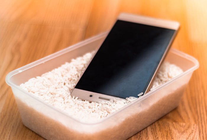 cell phone sitting in a tray full of white rice