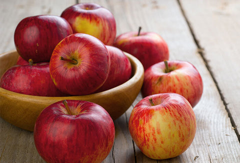 Wooden bowl filled with red apples.