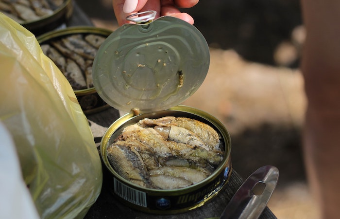 hand opening a can of anchovies