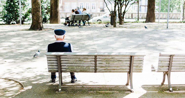 elderly man sitting alone on a park bench