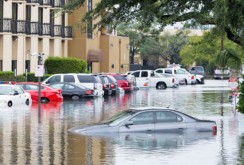 Flooding down a commercial street with water covering parked vehicles. 