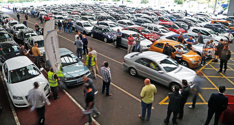 Used car dealers at an auto auction inspecting cars for sale.