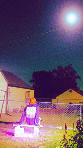 Person sitting under the moon in a hoodie
