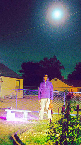 Person standing under the moon in a hoodie