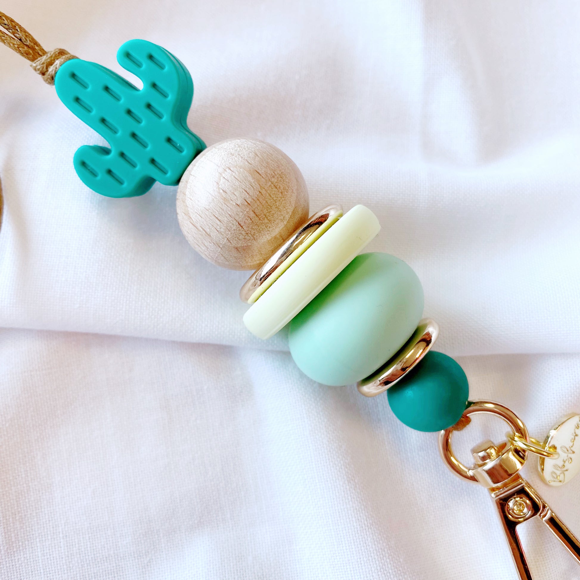 up close to the silicone beaded lanyard, showing mint, teal, green, wood and gold