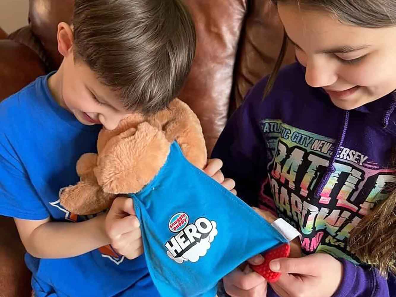 Young boy and young girl play with Snuggle Puppy HERO toy