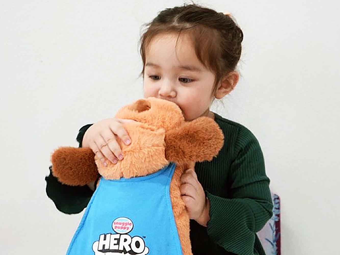 Young girl inspecting her Snuggle Puppy HERO toy