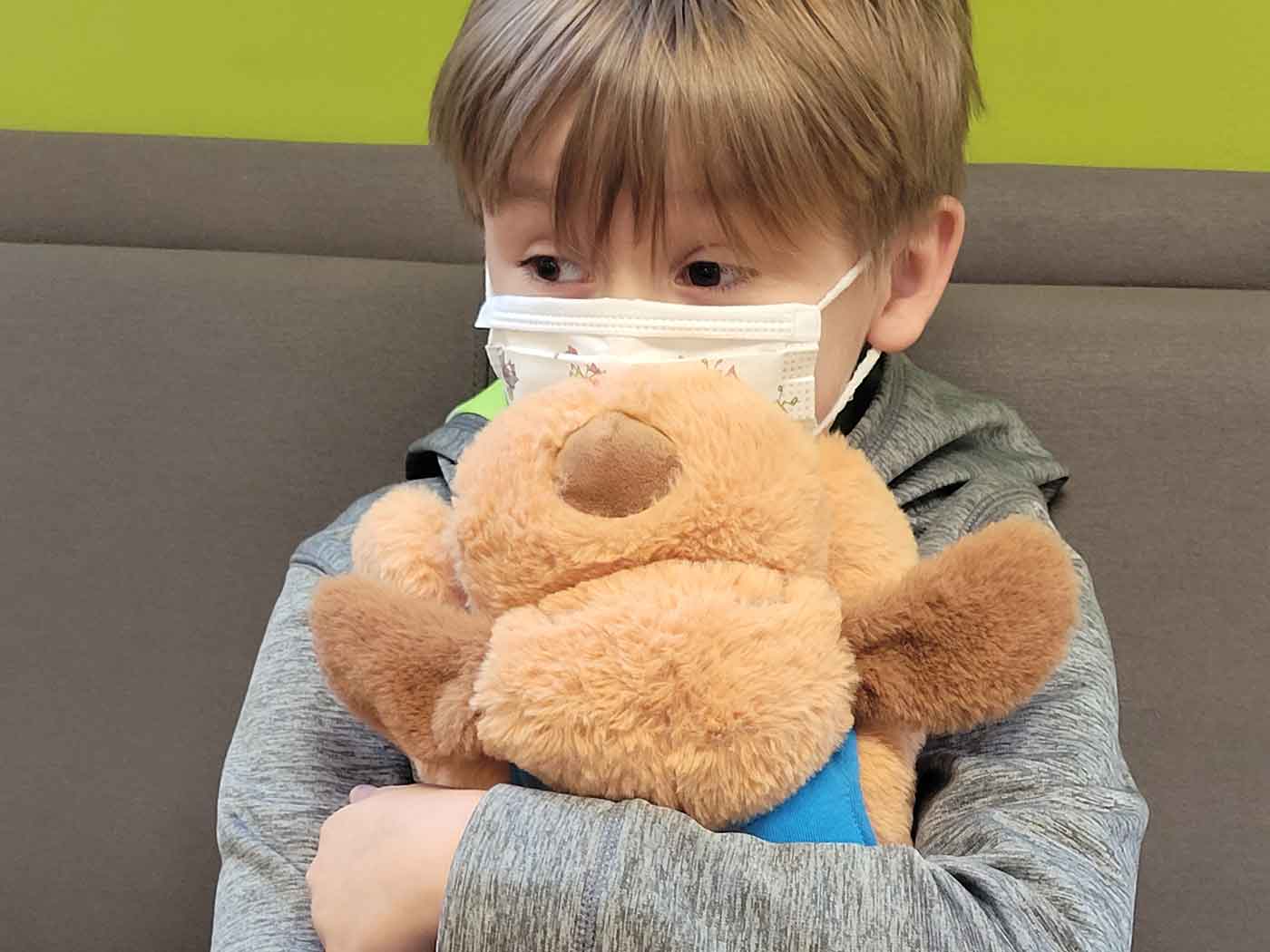 Young boy nervously waiting for an appointment with a Snuggle Puppy HERO toy