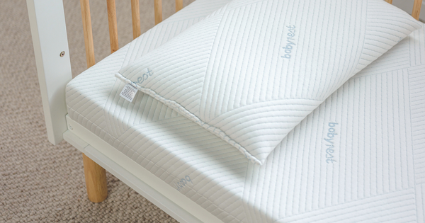 Close up of a Babyrest mattress and pillow in a cot setting. It looks soft and had the Babyrest branding in light blue in several places