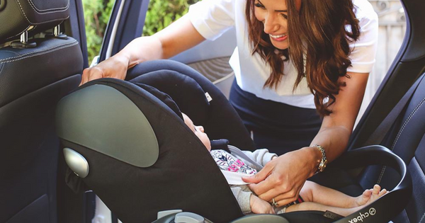 Smiling woman placing infant in Cybex Cloud Q capsule in car