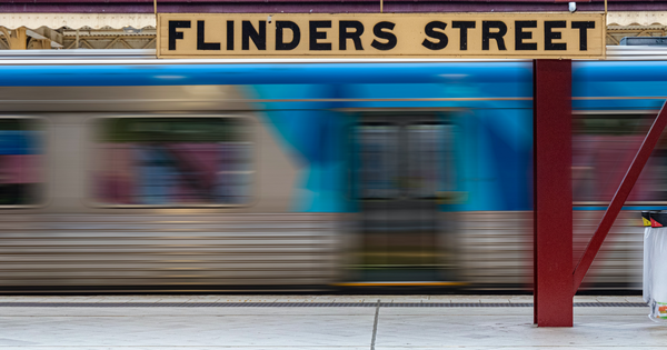 A train flashes past a Flinders Street Station sign