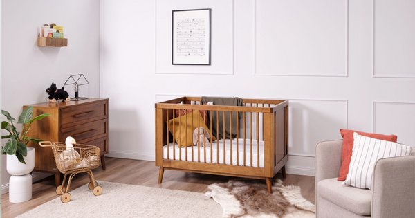 An elegant teak cot stands in the centre of a modern nursery