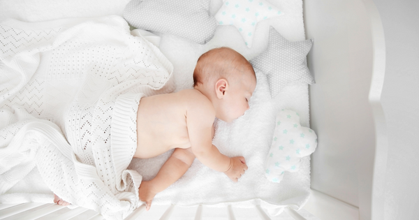 Baby surrounded by decorative pillows in a cot