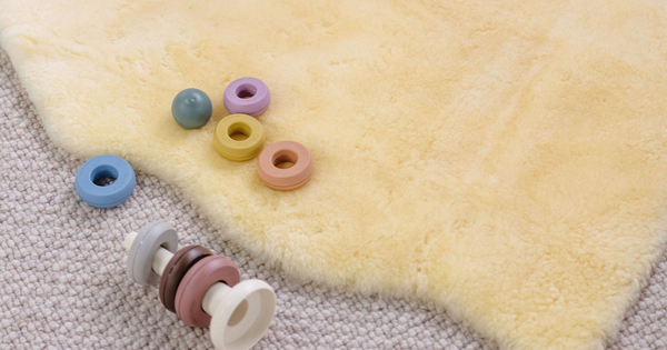 Closeup of a Babyrest lambskin rug next to some wooden toy blocks