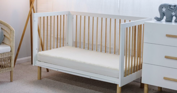 The Babyrest lambswool cot underlay pictured on a cot in a nursery setting