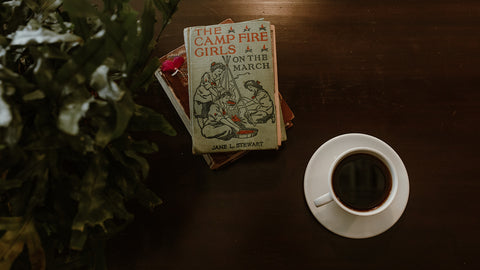A mug of coffee next to a plant and book