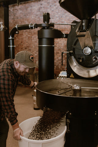 Director of Coffee Rob Maynard moving roasted coffee into a large bin and smiling while looking at it