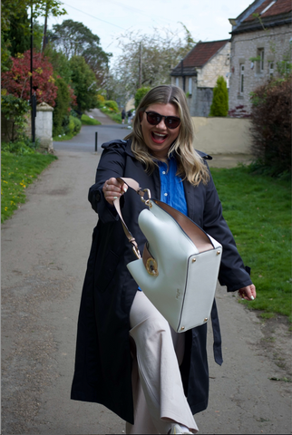 Woman in blue trench coat swinging her Luella Grey White and Mocha Tote Bag with joy