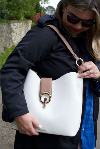 Woman holding her white and mocha tote bag for details of the clasps