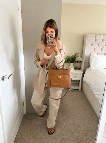 Woman in a beige bedroom and neutral outfit wearing a Luella Grey London Tote Bag in Camel and White