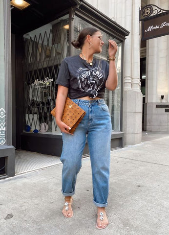 Woman standing on the street wearing a casual graphic t-shirt, jeans and sandals.
