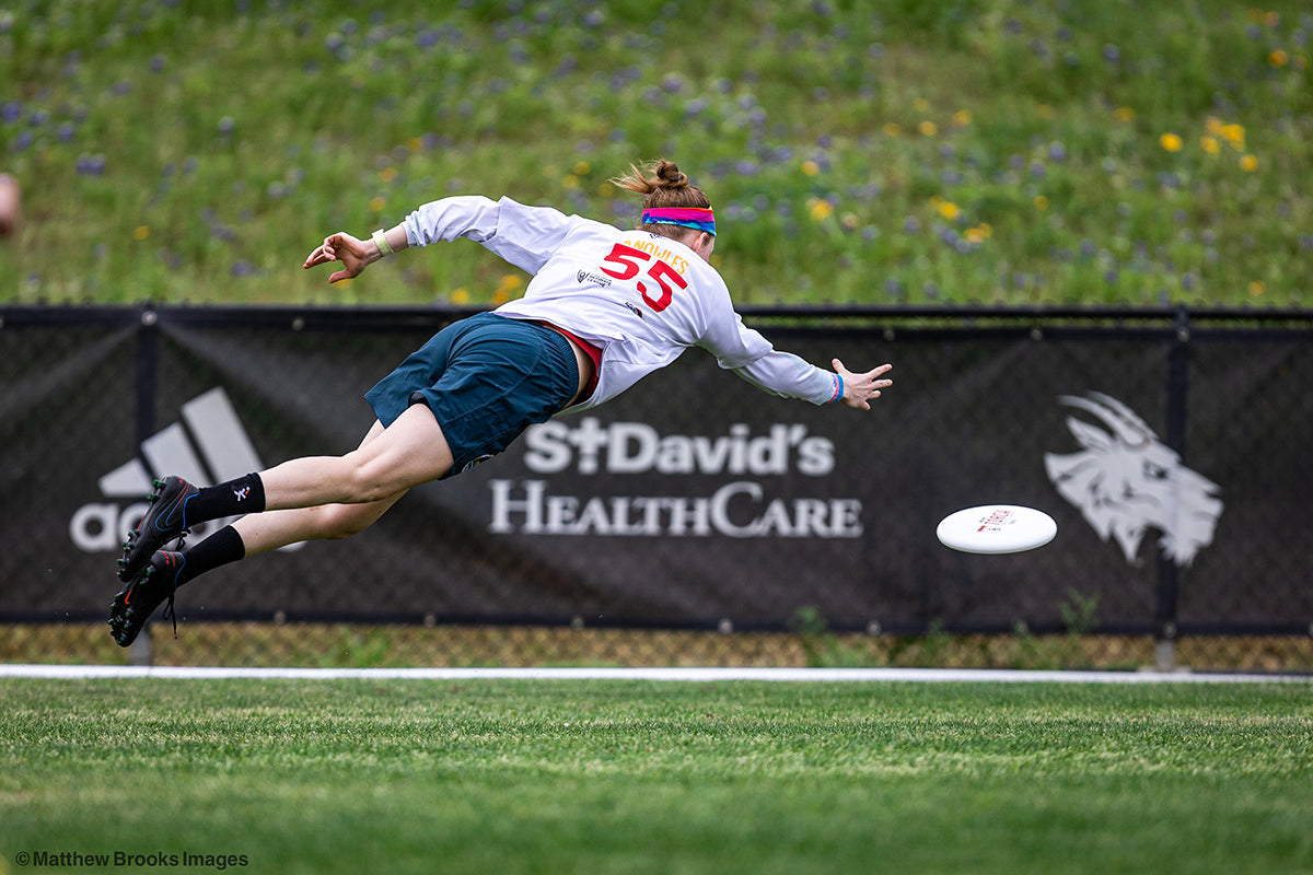 Rising Ultimate Player Lays Out To Grab Disc In Air - Photo Credit: Matthew Brooks