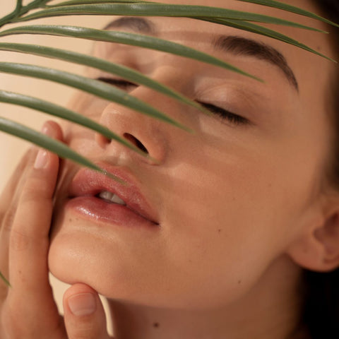 woman feeling her face with a plant in front