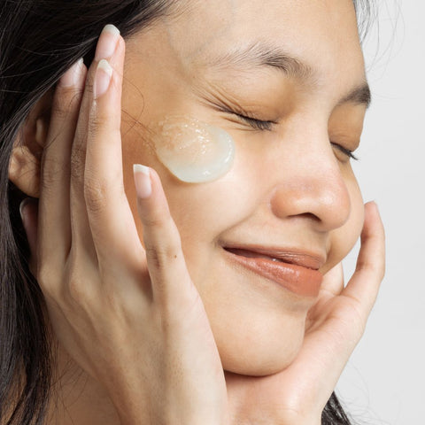 Woman smiles with cleanser on her face