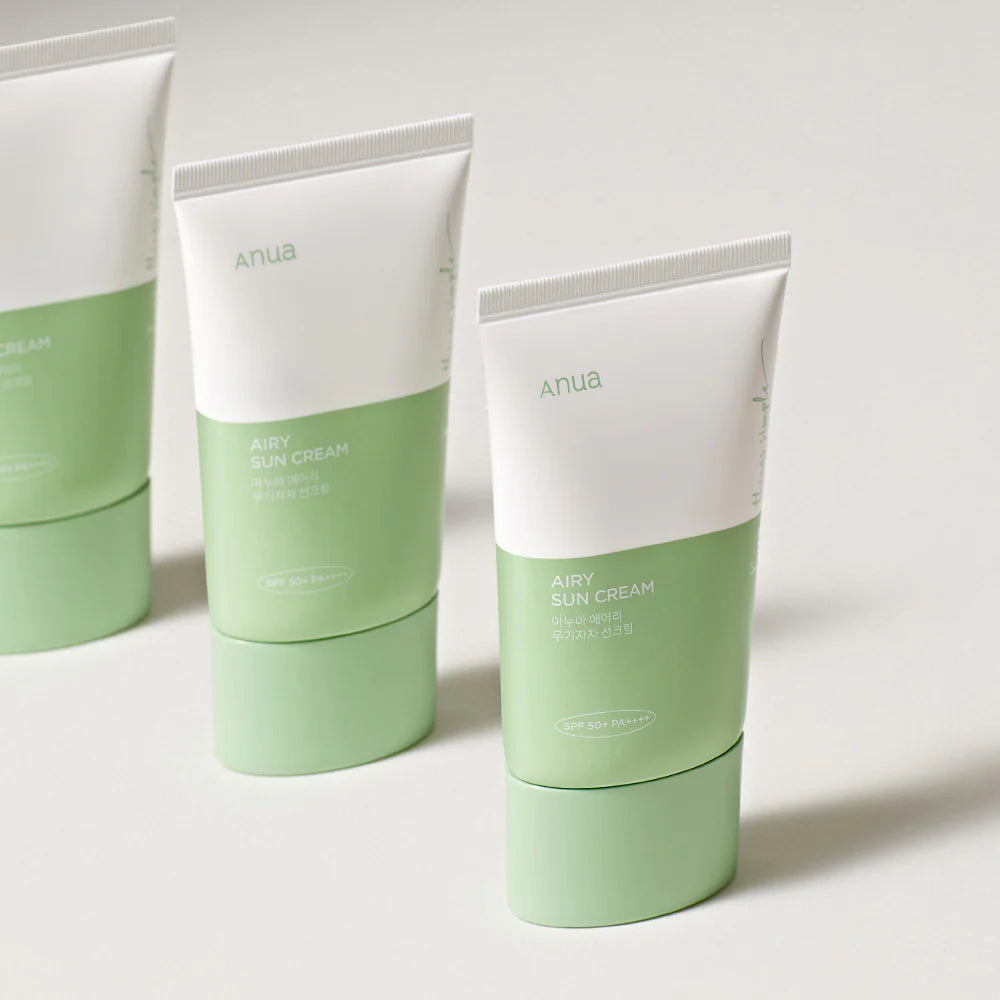 Two green and white tubes of Anua airy sun cream on a light background