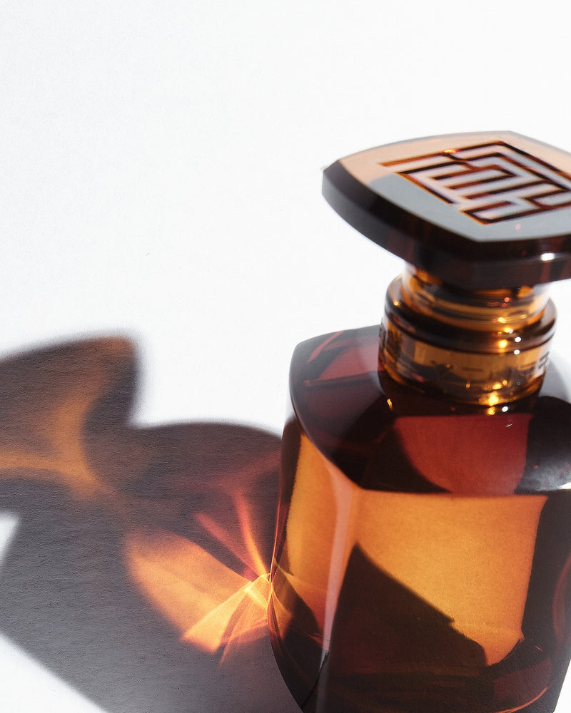 A bottle of Fenty Eau de Parfum and its shadow reflecting on white background.