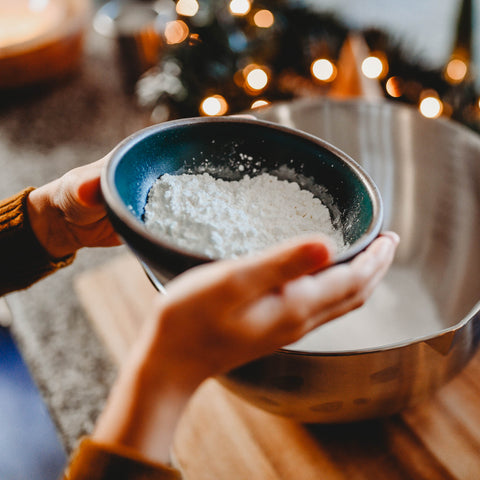 A child pouring ingredients for DIY Kid friendly bath bombs into mixing bowl. gift for santa