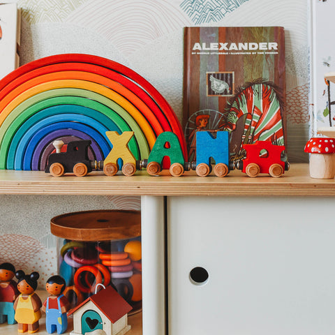 Maple Landmark Train and Grimm's wooden rainbow on a toy shelf.