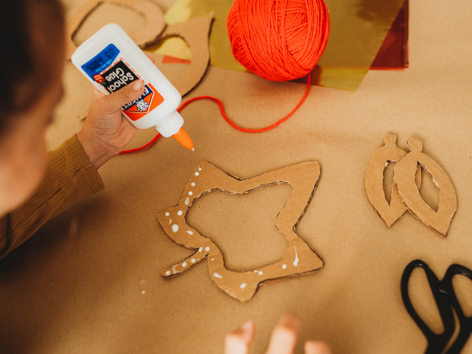 A child puts glue on cardboard for an eco-friendly fall crafts project