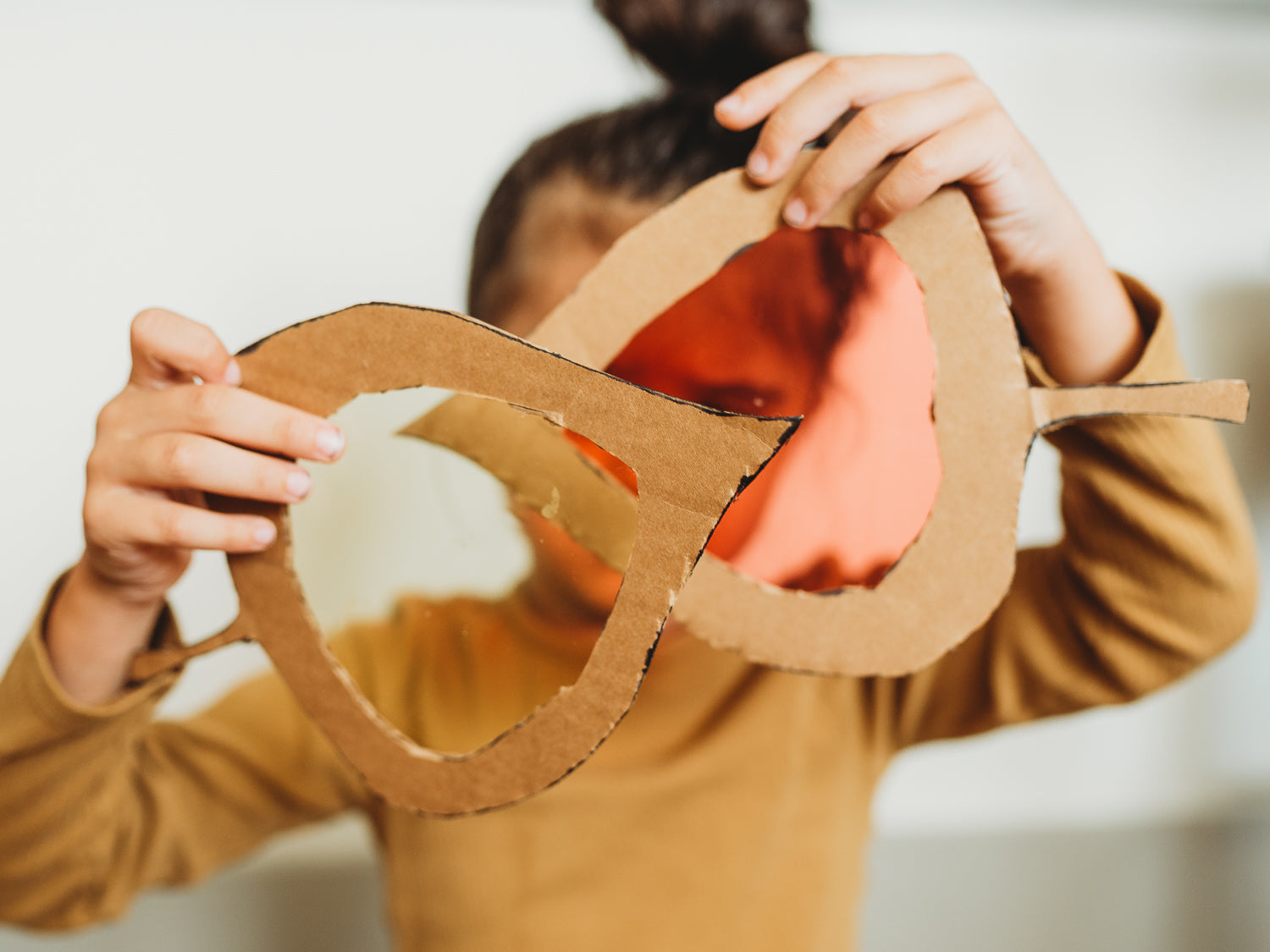 A child holds up cellophane and cardboard leaves to see the colors mix.)