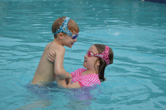 Two kids swimming in pool wearing Frogglez goggles
