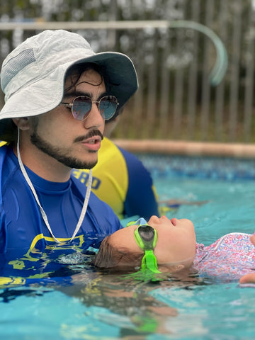 Swim instructor holding child as they learn to back float while wearing Frogglez Goggles