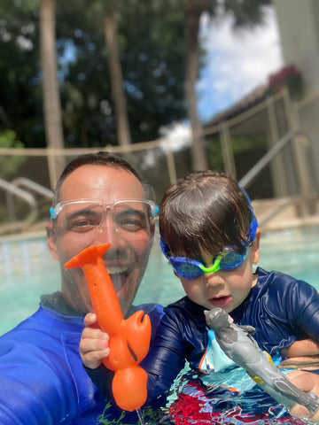 Young boy swimming in his swim lesson wearing Frogglez kids swim goggles with his swim instructor from Superhero Swim Academy 