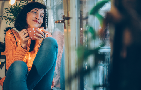 Woman relaxing at home drinking tea and smiling