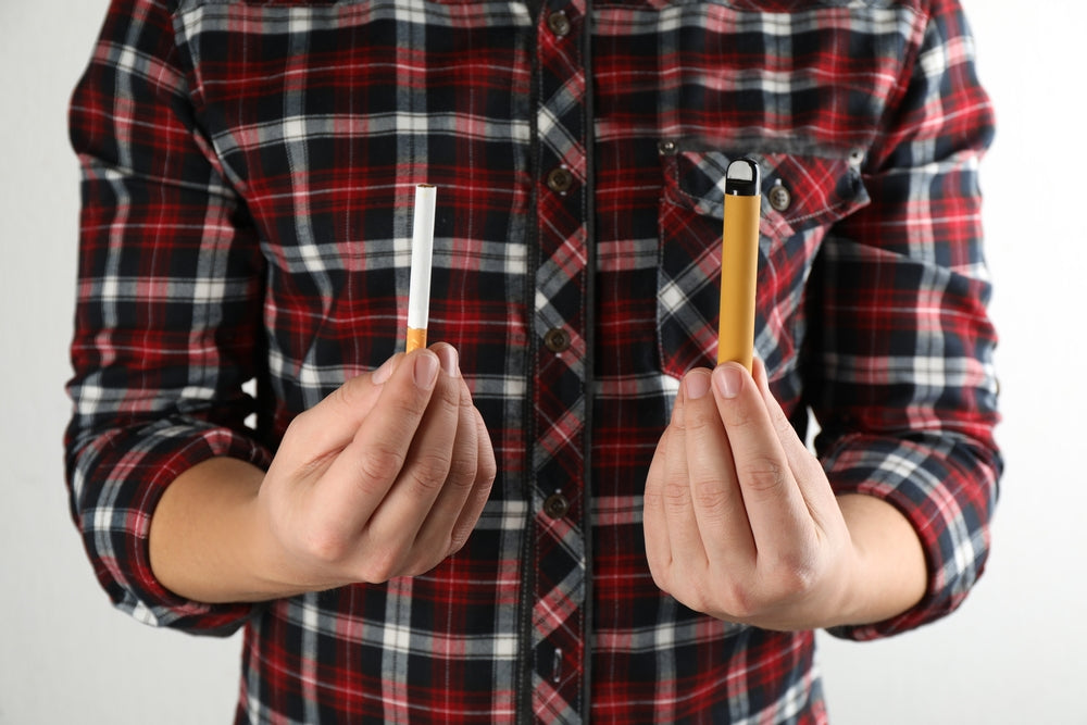Man holding cigarette and disposable vap 