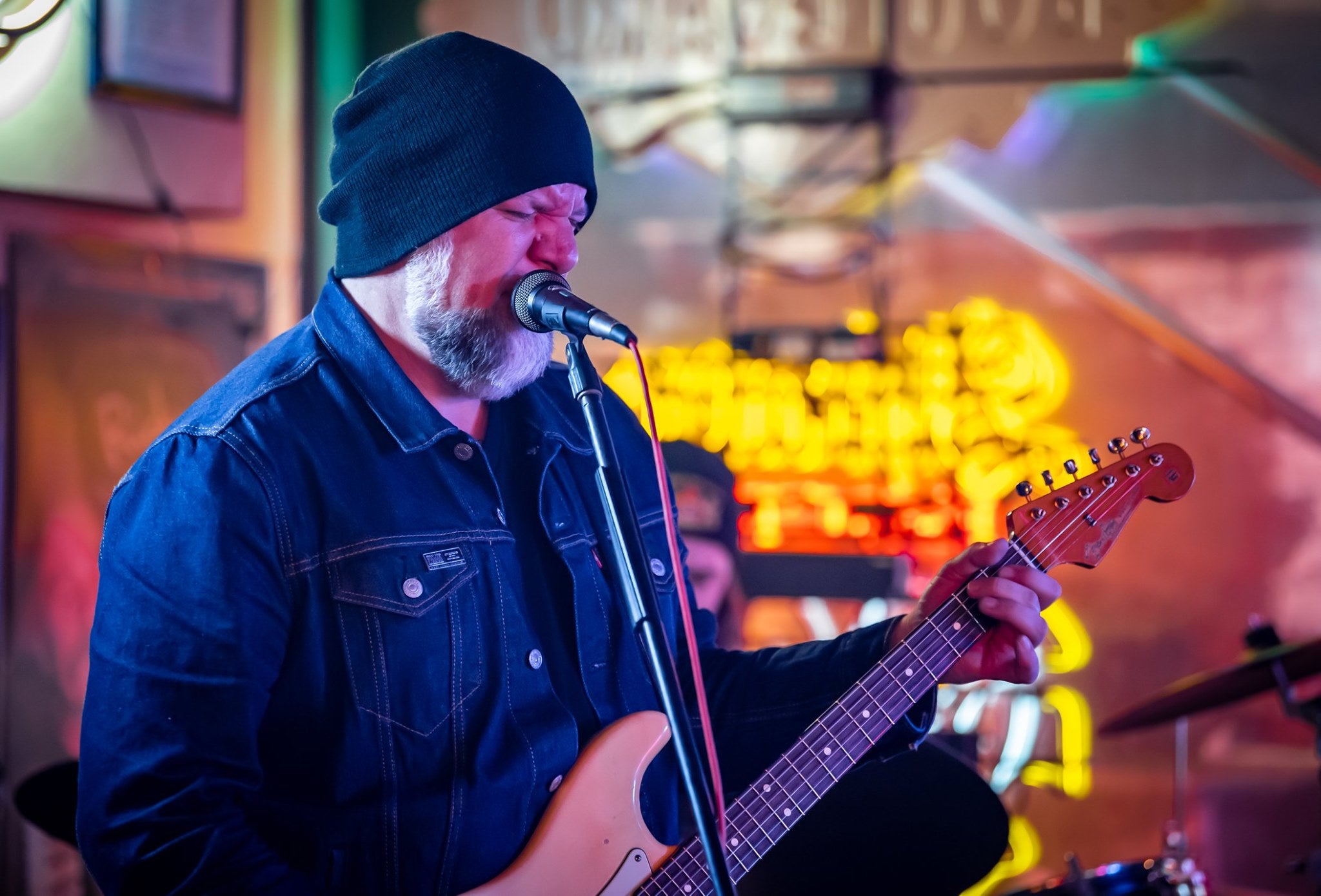 Man singing into microphone with guitar