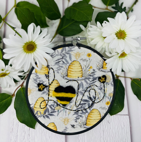 Bee lovers! Embroider “lve” with a Couching Stitch. Felt hearts with black wool. Felt yellow wool across large heart. Embroider Lazy Daisies on small hearts.