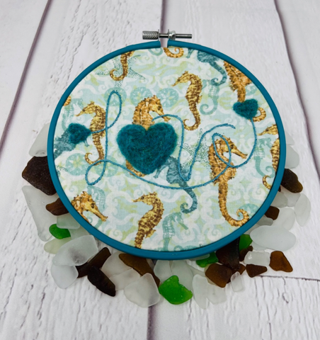 Seashores are the in animal for 2023!  Embroider “lve” with a Stem Stitch. Felt hearts in teal wool.