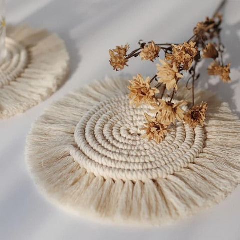 round white drink coasters in macramé boho style with fringes as decoration on a white table